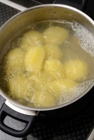 Boiling potatoes in a steel potの写真素材