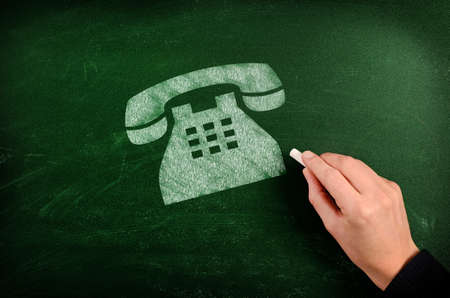Old phone symbol drawn with chalk on green chalkboardの写真素材