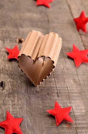 Love concept background with a heart shaped piece of cardboard on a rustic wooden tableの写真素材