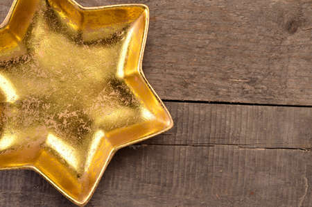 Golden star shaped bowl on a rustic wooden background with space for textの写真素材
