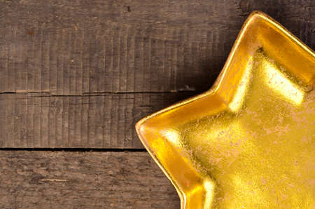 Empty golden star shaped bowl on a rustic wooden table with space for textの写真素材