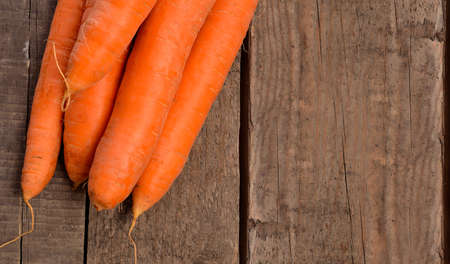 Fresh organic carrots on a rustic wooden table with space for textの写真素材