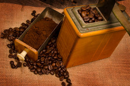 Old used coffee mill with coffee beans on a coffee bagの写真素材