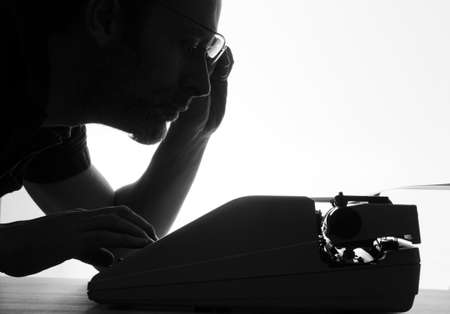 Man with an old typewriter, black and white with bright backgroundの写真素材