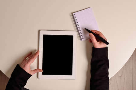 Businesswoman on an office table with a tablet computer and a notebook, top viewの写真素材