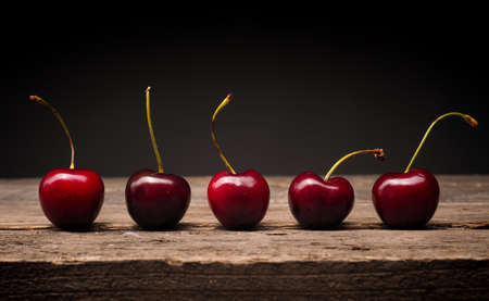 Five delicious big cherries on a rustic wooden table