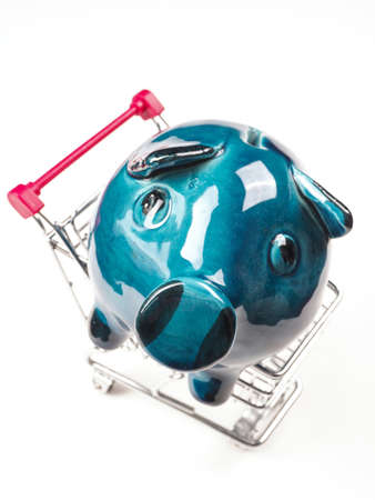 Old blue piggy bank with scratches in a shopping cart on a white backgroundの写真素材