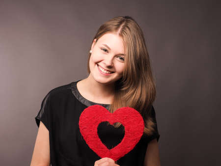 Young happy woman with shape of red heart, health care or love concept imageの写真素材