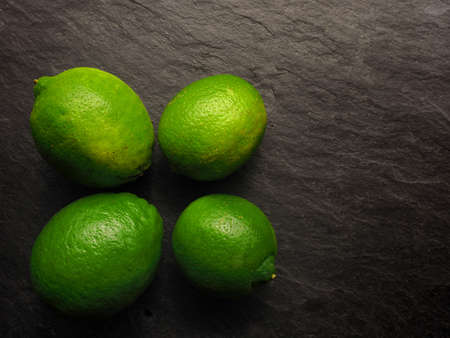 Fresh organic lime fruits on a dark slate background, healthy food background with space for textの写真素材