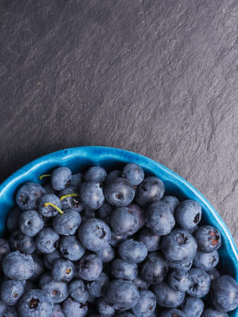 Fresh delicious blueberries in a rustic bowl on dark slate with space for textの写真素材