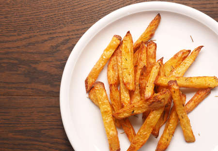 Homemade French fries with rosemary and thyme on a white plateの写真素材