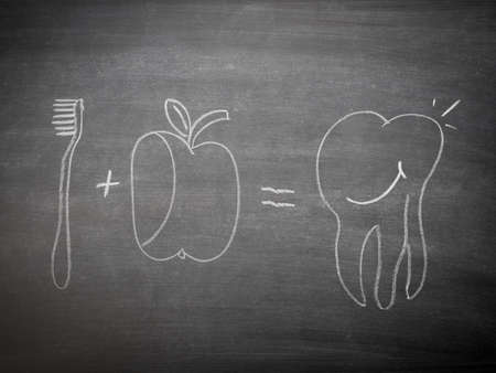 Tooth care concept on a blackboard, Hand drawm brush, apple and happy toothの写真素材