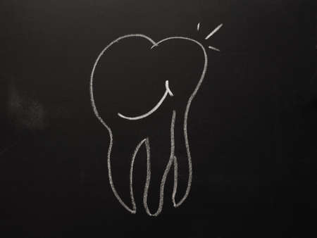 Hand drawn smiling tooth on a chalkboard, health care concept backgroundの写真素材