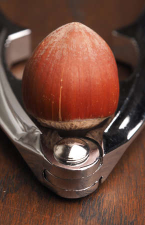 Close up of a hazelnut with a nutcracker on a wooden table
