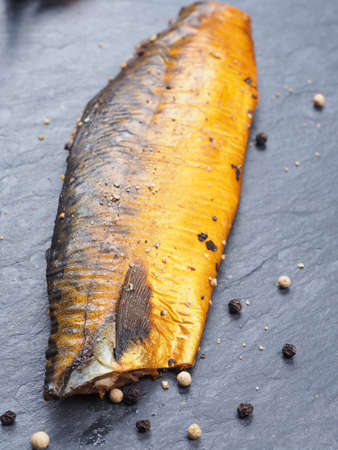 Smoked mackerel with pepper on dark slate plateの写真素材