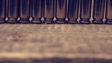 Close up of a row of bullets on a wooden table retro color tonedの写真素材