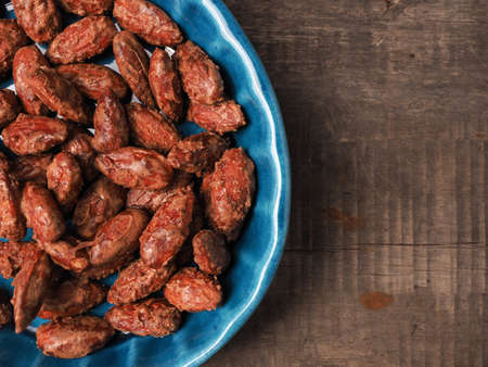 Tasty roasted almonds in a blue ceramic bowl with ingredients on wood