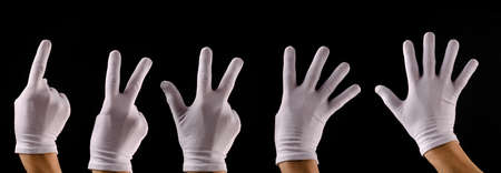 Hand with white gloves counting 1 to 5 on a dark backgroundの写真素材