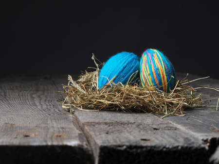 Two Easter eggs in a nest on a wooden table