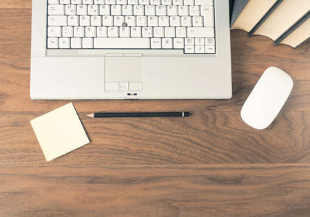 Laptop with books on a walnut desk with space for text or using as header, top viewの写真素材