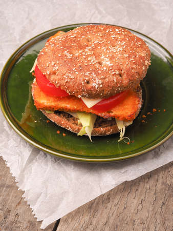 Homemade fish burger with organic ingredients on a rustic plateの写真素材