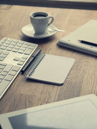 Espresso with notebooks and keyboard on wooden office table, hipster style background