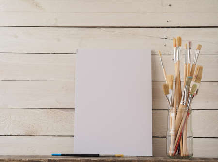 Paint brushes with a canvas on a white barn wood backgroundの写真素材
