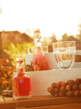 Summer drinks in a rustic wooden box with glasses in a garden at sundownの写真素材