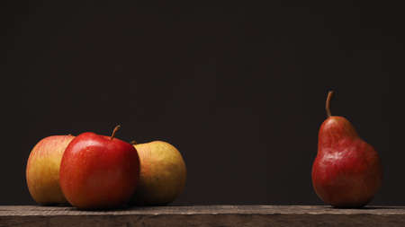 Three apples and one pear on a rustic wooden table, using as background with space for textの写真素材