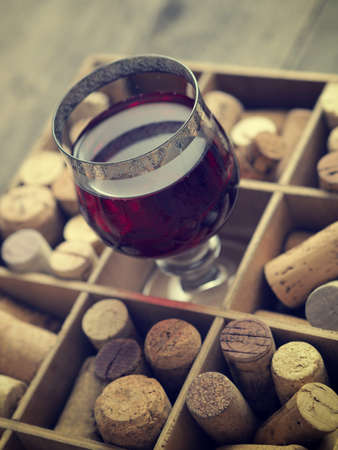 Close up of a glass of red wine with bottle corks, selective focus on the glassの写真素材