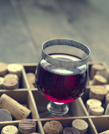 Glass of red wine in a wooden box with bottle cork, vintage color tonedの写真素材