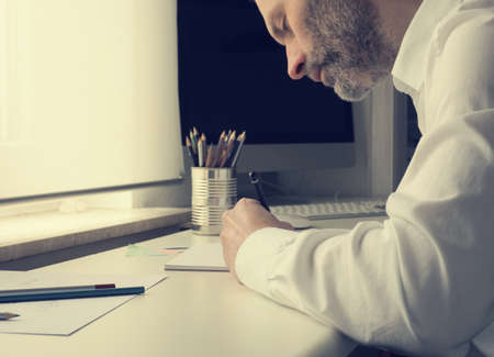 Man is drawing on a paper sheet, creativity concept with natural light in an officeの写真素材