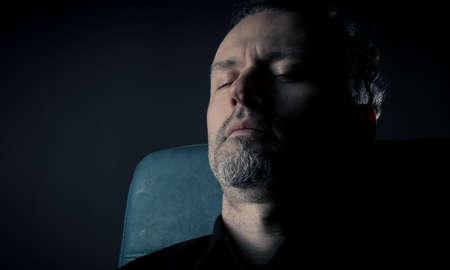 close up of a man sleeping on a leather chairの写真素材