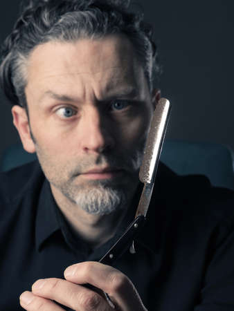 Handsome man with a rusty old shaving knife looking scary