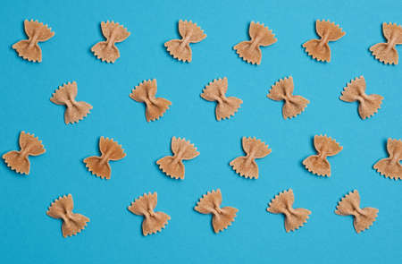 Pasta or noodles background, whole grain farfalle on blue, food concepts, view from aboveの写真素材