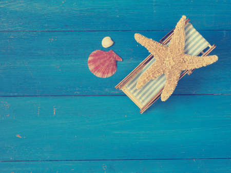 Starfish resting in a deckchair on a blue wooden background with space for textの写真素材