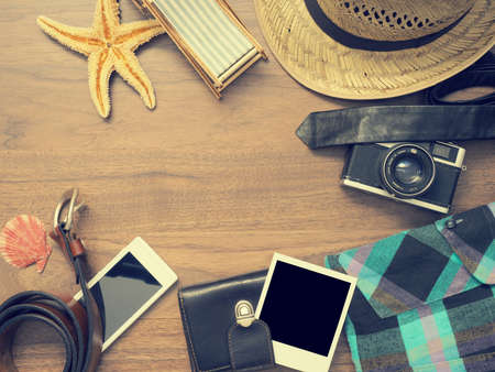 Vintage color toned travel background with clothing and camera on a wooden tableの写真素材
