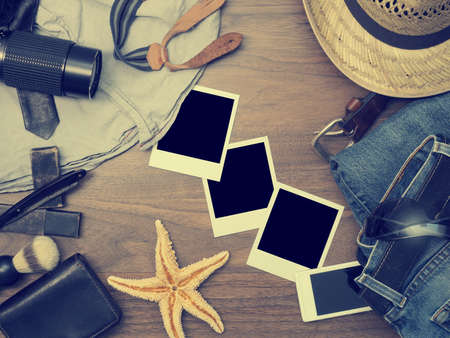 Vintage color toned travel background with clothing and camera on a wooden table
