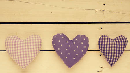 Heart shapes of fabric on a wooden table, greeting cards background with space for text, retro color tonedの写真素材