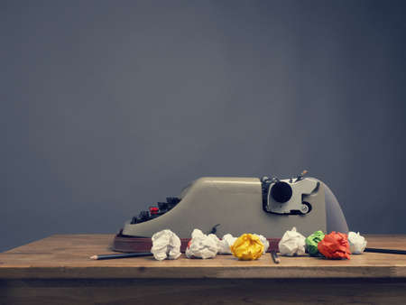 Crumpled paper with an old typewriter on a wooden office desk, creativity conceptの写真素材