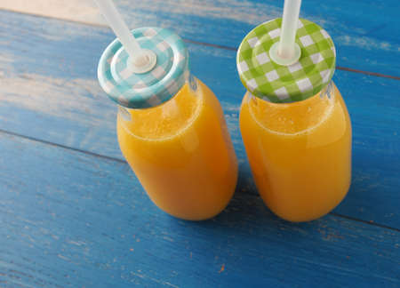 Fresh organic orange juice on a blue weathered tableの写真素材