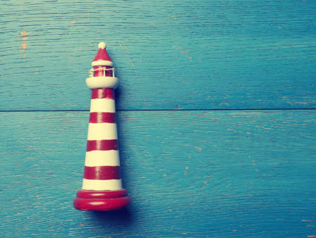 Small lighthouse on a rustic wooden background using as vacation cardの写真素材