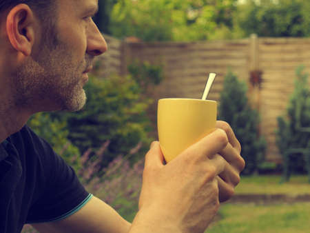 Bearded man with a cup of coffee in the garden, have a break conceptの写真素材