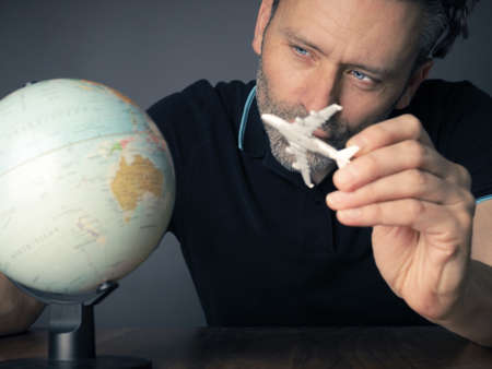 Handsome man looking a small globe to find the next travel destination