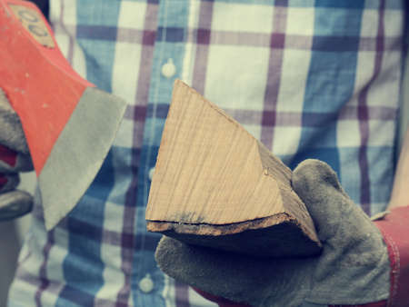 Young man holding an axe and fire wood, selective focus on wood, retro film stylized, alternative energy conceptの写真素材