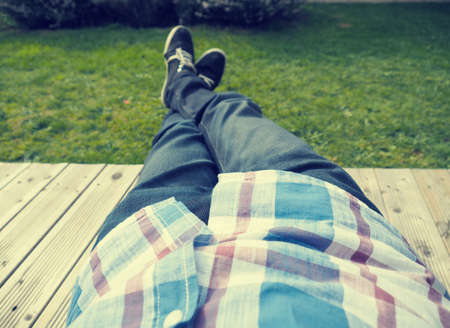 Young man relaxing on a wooden terrace after work, retro stylizedの写真素材