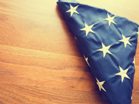 Folded American flag into a triangular shape on an old walnut office table with space for text or...