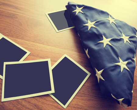 Old photo frames with a folded American flag on a wooden tableの写真素材