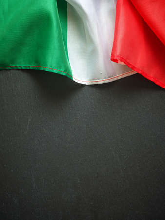 Flag of Italy on a dark slate texture, using as menu or travel background with space for text or imageの写真素材