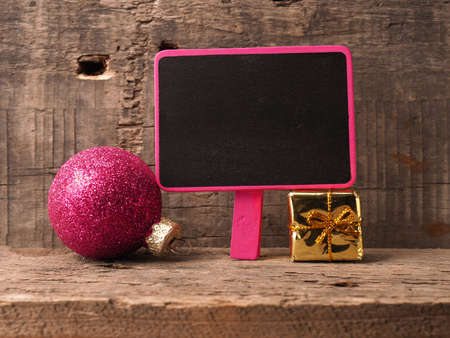 Small chalkboartd with an old Christmas bauble and gift box on a rustic wooden backgroundの写真素材